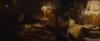 Movie still from “The Diary of a Teenage Girl” (2015), directed by Marielle Heller – A woman sitting on a bed in a room with a lot of papers on the floor; Medium shot, High angle