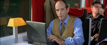 Movie still from “Le Dîner de Cons” (1998), directed by Francis Veber – A man sitting in front of a laptop computer; Medium shot, High angle