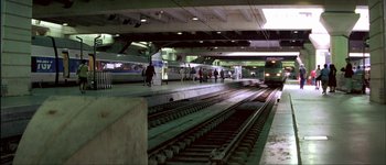 Movie still from “Le Dîner de Cons” (1998), directed by Francis Veber – People are walking on the tracks at a train station; Extreme Wide shot, High angle