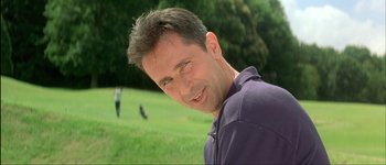 Movie still from “Le Dîner de Cons” (1998), directed by Francis Veber – A person smiling in a field; Close Up shot, Low angle