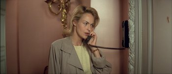 Movie still from “Le Dîner de Cons” (1998), directed by Francis Veber – A woman talking on a phone while wearing a trench coat; Close Up shot, High angle