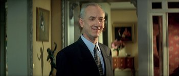 Movie still from “Le Dîner de Cons” (1998), directed by Francis Veber – A person wearing a suit and tie; Close Up shot, Low angle