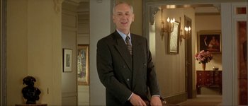 Movie still from “Le Dîner de Cons” (1998), directed by Francis Veber – A man in a suit and tie standing in front of a mirror; Medium shot, Low angle