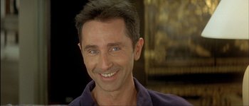 Movie still from “Le Dîner de Cons” (1998), directed by Francis Veber – A person with a smile on their face; Close Up shot, Low angle