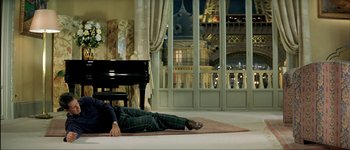 Movie still from “Le Dîner de Cons” (1998), directed by Francis Veber – A man laying on the floor next to a piano; Wide shot, High angle