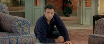 Movie still from “Le Dîner de Cons” (1998), directed by Francis Veber – A man laying on the ground in front of a door; Medium shot, Over the shoulder angle