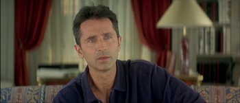 Movie still from “Le Dîner de Cons” (1998), directed by Francis Veber – A person sitting in front of a window; Close Up shot, Over the shoulder angle
