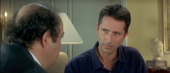 Movie still from “Le Dîner de Cons” (1998), directed by Francis Veber – A man in a blue shirt talking to another man in a blue shirt; Close Up shot, Over the shoulder angle