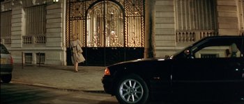 Movie still from “Le Dîner de Cons” (1998), directed by Francis Veber – A woman walking down the street in front of a car; Wide shot, High angle