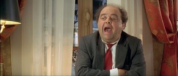 Movie still from “Le Dîner de Cons” (1998), directed by Francis Veber – A person wearing a suit and tie; Close Up shot, Low angle