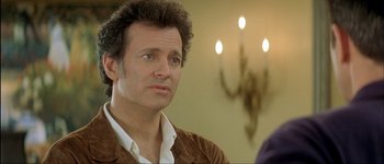 Movie still from “Le Dîner de Cons” (1998), directed by Francis Veber – A person wearing a brown jacket; Close Up shot, Over the shoulder angle