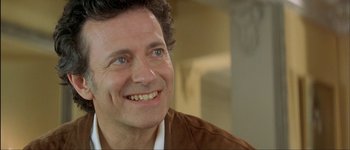 Movie still from “Le Dîner de Cons” (1998), directed by Francis Veber – A person with a smile on his face; Close Up shot, Over the shoulder angle