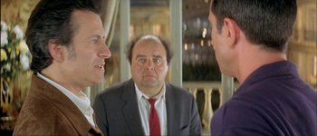 Movie still from “Le Dîner de Cons” (1998), directed by Francis Veber – A man in a suit and tie looking at two other men in front of a mirror; Close Up shot, Over the shoulder angle