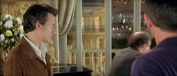 Movie still from “Le Dîner de Cons” (1998), directed by Francis Veber – A man sitting in front of a piano in front of a window; Close Up shot, Over the shoulder angle