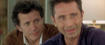 Movie still from “Le Dîner de Cons” (1998), directed by Francis Veber – A couple of men sitting next to each other; Close Up shot, Over the shoulder angle