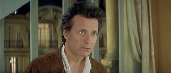 Movie still from “Le Dîner de Cons” (1998), directed by Francis Veber – A person wearing a brown jacket; Close Up shot, Over the shoulder angle