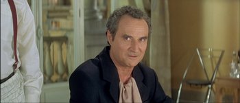 Movie still from “Le Dîner de Cons” (1998), directed by Francis Veber – An older man wearing a jacket and a tie; Close Up shot, Over the shoulder angle