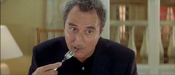 Movie still from “Le Dîner de Cons” (1998), directed by Francis Veber – A person with a fork in their mouth; Close Up shot, Low angle