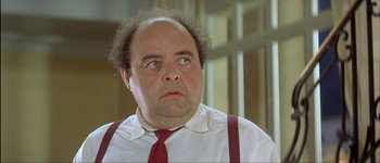 Movie still from “Le Dîner de Cons” (1998), directed by Francis Veber – A man with a beard wearing a red neck tie; Close Up shot, Low angle