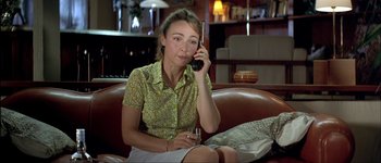 Movie still from “Le Dîner de Cons” (1998), directed by Francis Veber – A woman sitting on a couch talking on a phone; Medium shot, High angle