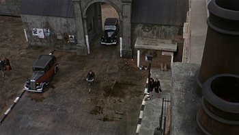 Movie still from “The Dirty Dozen” (1967), directed by Robert Aldrich – A couple of people riding bikes in a garage; Extreme Wide shot, Overhead angle