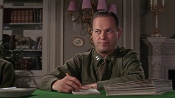 Movie still from “The Dirty Dozen” (1967), directed by Robert Aldrich – A man sitting at a table writing on a piece of paper; Medium shot, Low angle
