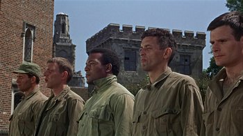 Movie still from “The Dirty Dozen” (1967), directed by Robert Aldrich – A group of men standing next to each other in front of a building; Medium shot, Low angle