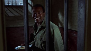 Movie still from “The Dirty Dozen” (1967), directed by Robert Aldrich – A man standing behind bars in a jail cell; Close Up shot, High angle
