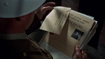 Movie still from “The Dirty Dozen” (1967), directed by Robert Aldrich – A man in uniform looking at an old document; Close Up shot, Over the shoulder angle
