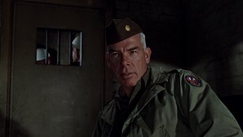 Movie still from “The Dirty Dozen” (1967), directed by Robert Aldrich – A man in a military uniform standing in front of a window; Close Up shot, Low angle