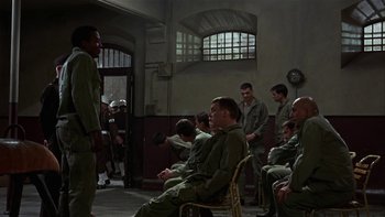 Movie still from “The Dirty Dozen” (1967), directed by Robert Aldrich – A group of men sitting and standing in a room; Wide shot, High angle