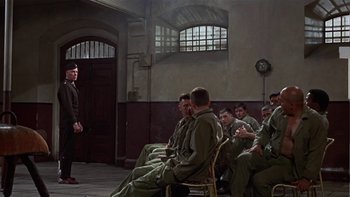 Movie still from “The Dirty Dozen” (1967), directed by Robert Aldrich – A group of men sitting on chairs in a room; Wide shot, High angle