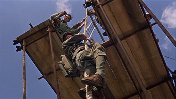 Movie still from “The Dirty Dozen” (1967), directed by Robert Aldrich – Two men are climbing on a wooden structure; Wide shot, Low angle