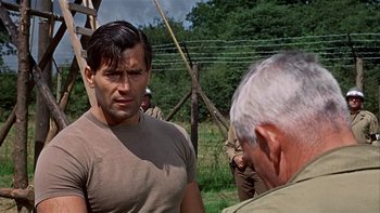 Movie still from “The Dirty Dozen” (1967), directed by Robert Aldrich – A man standing next to another man on a field; Medium shot, Over the shoulder angle