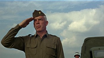 Movie still from “The Dirty Dozen” (1967), directed by Robert Aldrich – An older man saluting in front of a sky background; Medium shot, Low angle