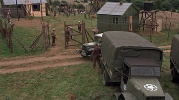 Movie still from “The Dirty Dozen” (1967), directed by Robert Aldrich – A group of men standing next to an army vehicle; Extreme Wide shot, High angle