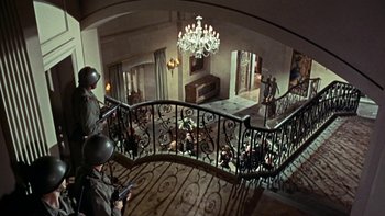 Movie still from “The Dirty Dozen” (1967), directed by Robert Aldrich – Two men are standing on the stairs of a house; Wide shot, High angle