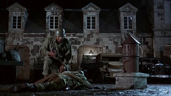 Movie still from “The Dirty Dozen” (1967), directed by Robert Aldrich – A man kneeling down next to a dead body; Wide shot, High angle