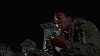 Movie still from “The Dirty Dozen” (1967), directed by Robert Aldrich – A man holding a gun while sitting on a bench; Close Up shot, Low angle