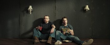 Movie still from “The Disappearance of Alice Creed” (2009), directed by J Blakeson – A couple of men sitting next to each other on the ground; Medium shot, Low angle