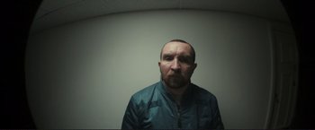 Movie still from “The Disappearance of Alice Creed” (2009), directed by J Blakeson – A man in a green jacket is looking at the camera; Close Up shot, Low angle