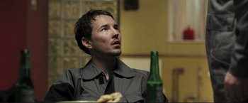 Movie still from “The Disappearance of Alice Creed” (2009), directed by J Blakeson – A man sitting in front of a bottle of beer; Close Up shot, Low angle