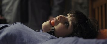 Movie still from “The Disappearance of Alice Creed” (2009), directed by J Blakeson – A woman with a collar around her neck is laying on a bed; Close Up shot, High angle