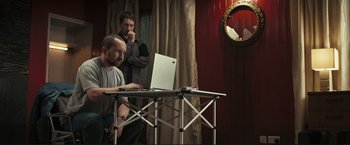 Movie still from “The Disappearance of Alice Creed” (2009), directed by J Blakeson – Two men sitting at a table with a laptop computer; Medium shot, Over the shoulder angle