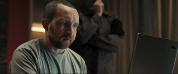 Movie still from “The Disappearance of Alice Creed” (2009), directed by J Blakeson – A man standing next to another man in a room; Close Up shot, Over the shoulder angle
