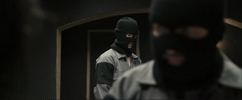 Movie still from “The Disappearance of Alice Creed” (2009), directed by J Blakeson – A man wearing a black mask is standing in front of another man wearing a black balaclava; Close Up shot, Over the shoulder angle
