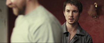 Movie still from “The Disappearance of Alice Creed” (2009), directed by J Blakeson – A man with a beard is looking at himself in the mirror; Close Up shot, Over the shoulder angle