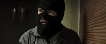 Movie still from “The Disappearance of Alice Creed” (2009), directed by J Blakeson – A man wearing a black balaclava and a gray shirt; Close Up shot, Over the shoulder angle