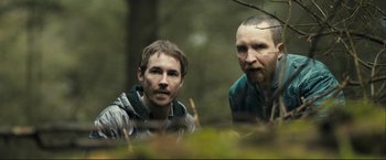 Movie still from “The Disappearance of Alice Creed” (2009), directed by J Blakeson – Two men are sitting in the woods looking at the camera; Close Up shot, Low angle