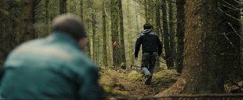 Movie still from “The Disappearance of Alice Creed” (2009), directed by J Blakeson – A man is walking through the woods on a trail; Wide shot, Over the shoulder angle